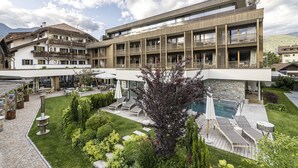 A modern building with multiple balconies, a swimming pool, and outdoor seating areas. - Hotel Langgenhof (Brunico)