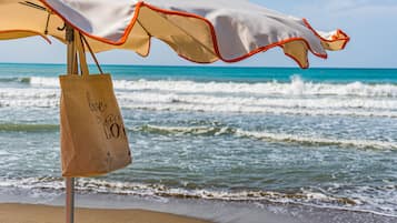 Relax by the ocean with a beach umbrella and a nearby beach bag.