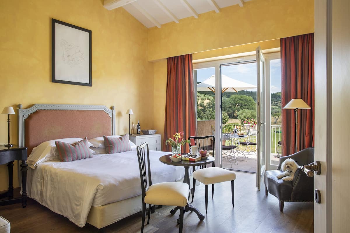 Una habitación de hotel con cama, mesa de comedor, sillas y un balcón con vistas.