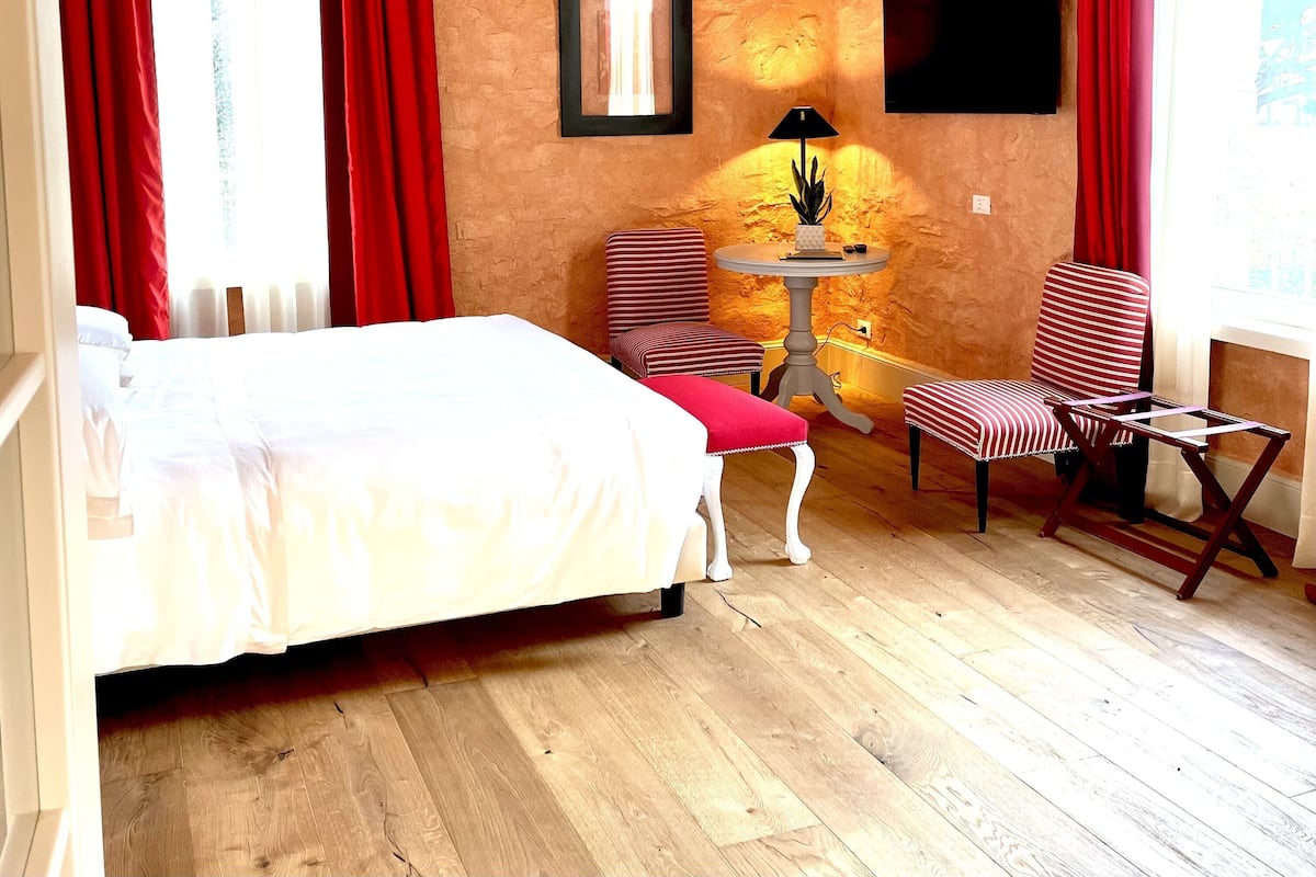 Una habitación con cama, una silla, una mesa y un televisor.