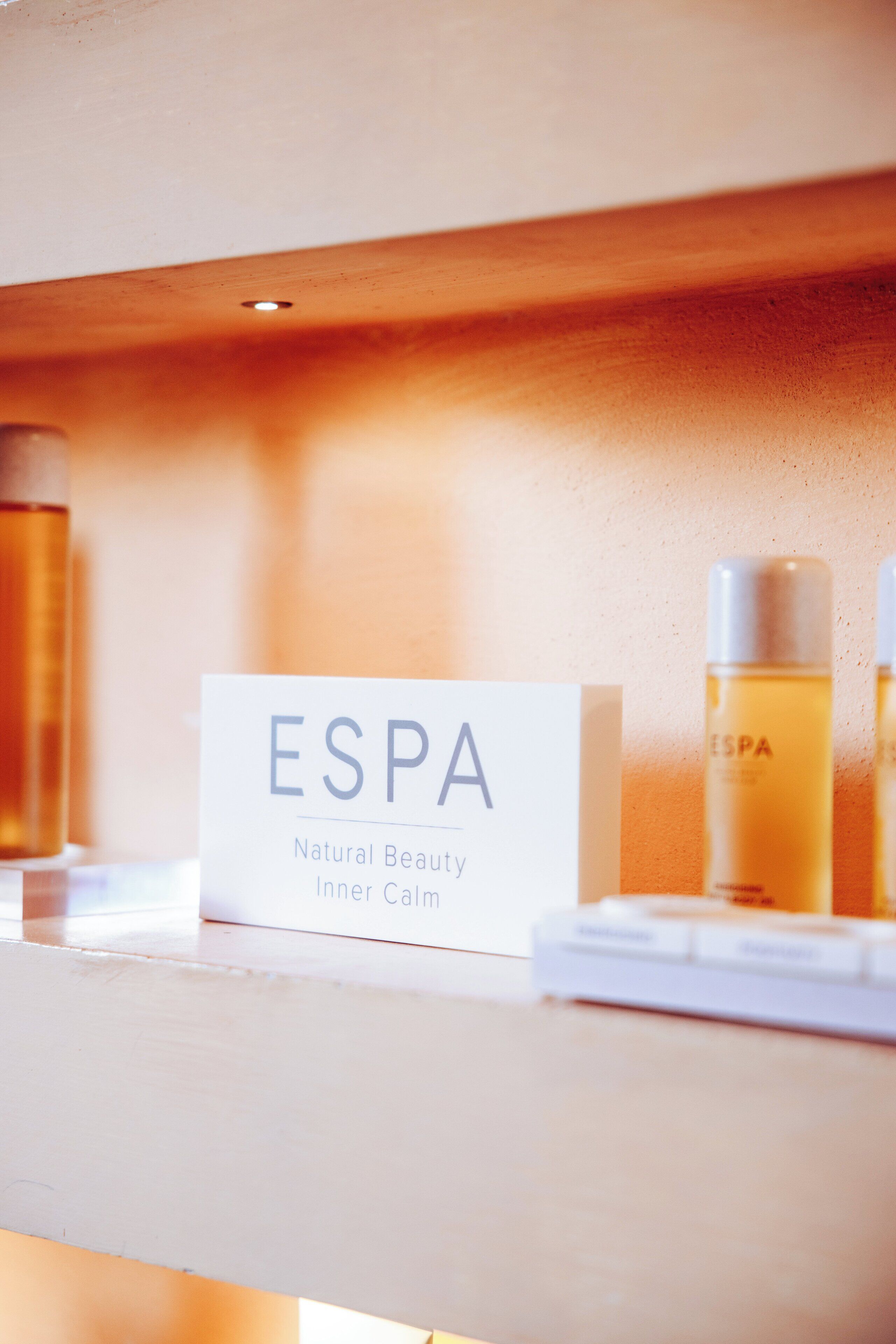 A shelf with a sign labeled "ESPA" and two bottles of liquid.