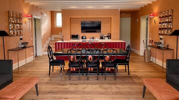 A modern kitchen with a dining area, featuring a large TV, a red and white striped table, and black chairs.