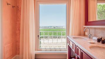 Ein Badezimmer mit einem großen Fenster, einem Waschbecken und einem Spiegel.
