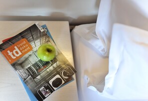 A magazine on a bed with a green apple on top.