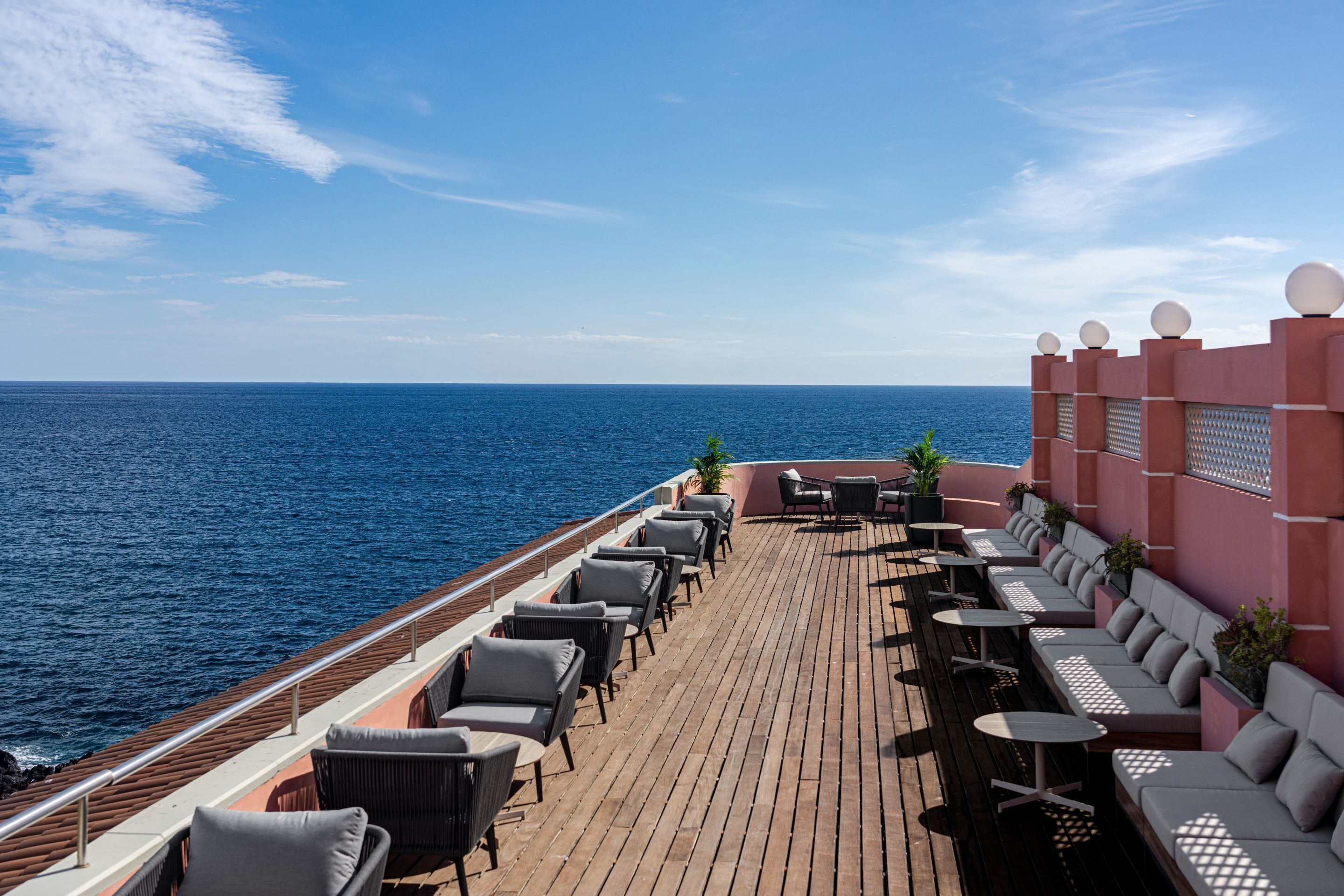 Een terras met zitplaatsen buiten en uitzicht op de oceaan.