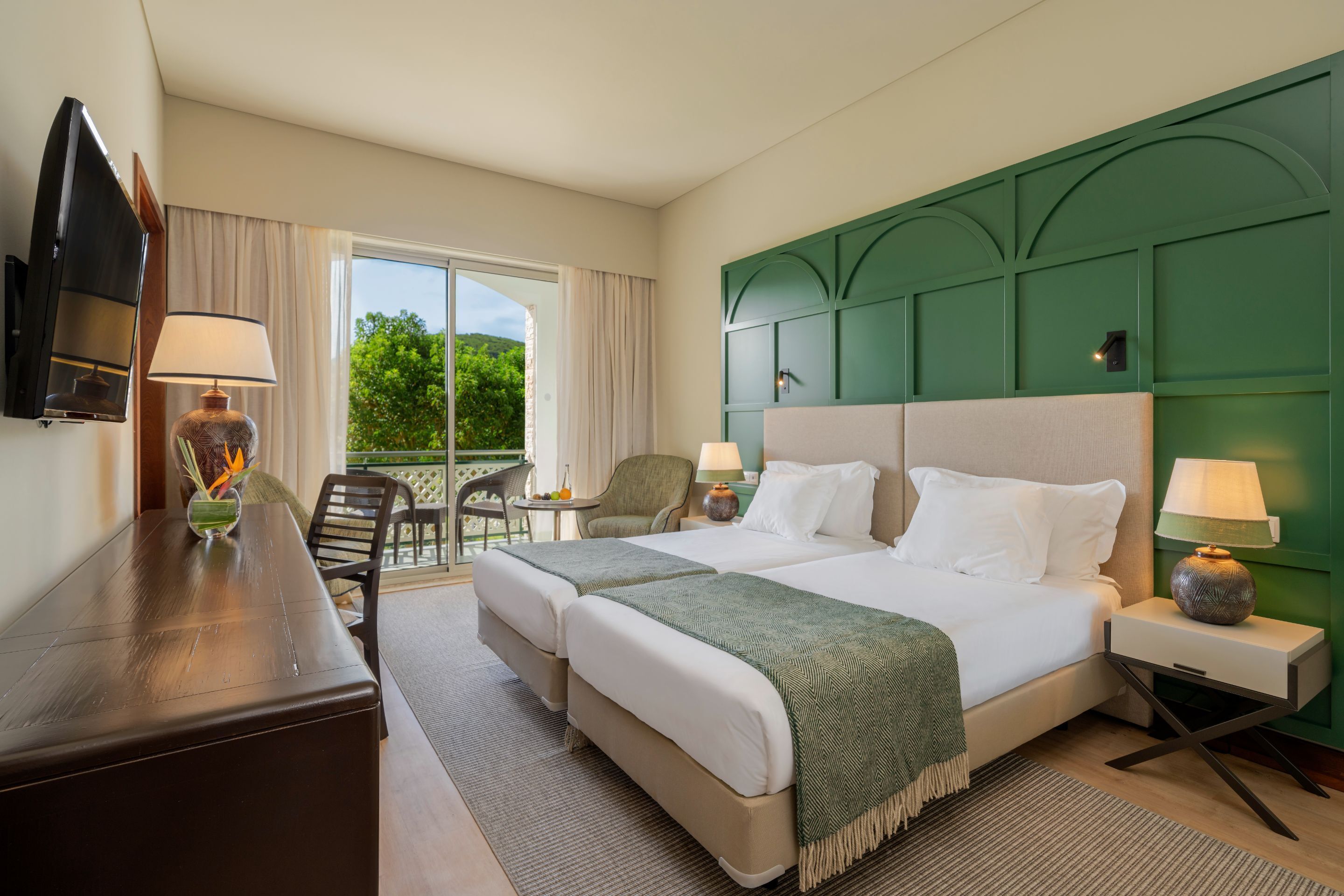 Une chambre d’hôtel avec un grand lit, deux tables de chevet, un bureau, une chaise et un téléviseur.
