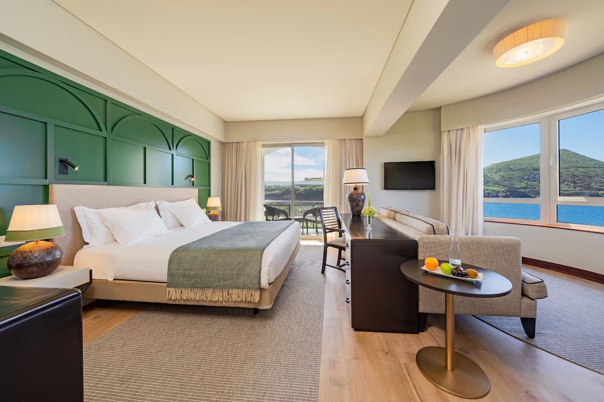 Une chambre d’hôtel équipée d’un lit, d’un bureau, d’une chaise, d’une télévision et offrant une vue sur l’extérieur.