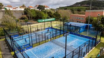 An indoor swimming pool with multiple lanes, surrounded by a fence, and a banner for 'Acores Fusion Club'.