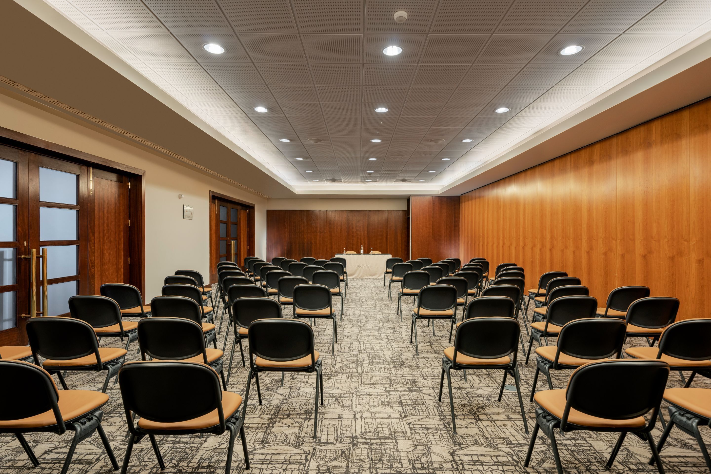 A conference room with rows of chairs, a podium, and a carpeted floor.