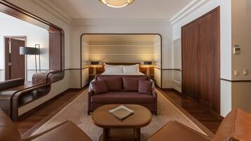 A modern hotel room with a large bed, a sofa, a coffee table, and a wardrobe.