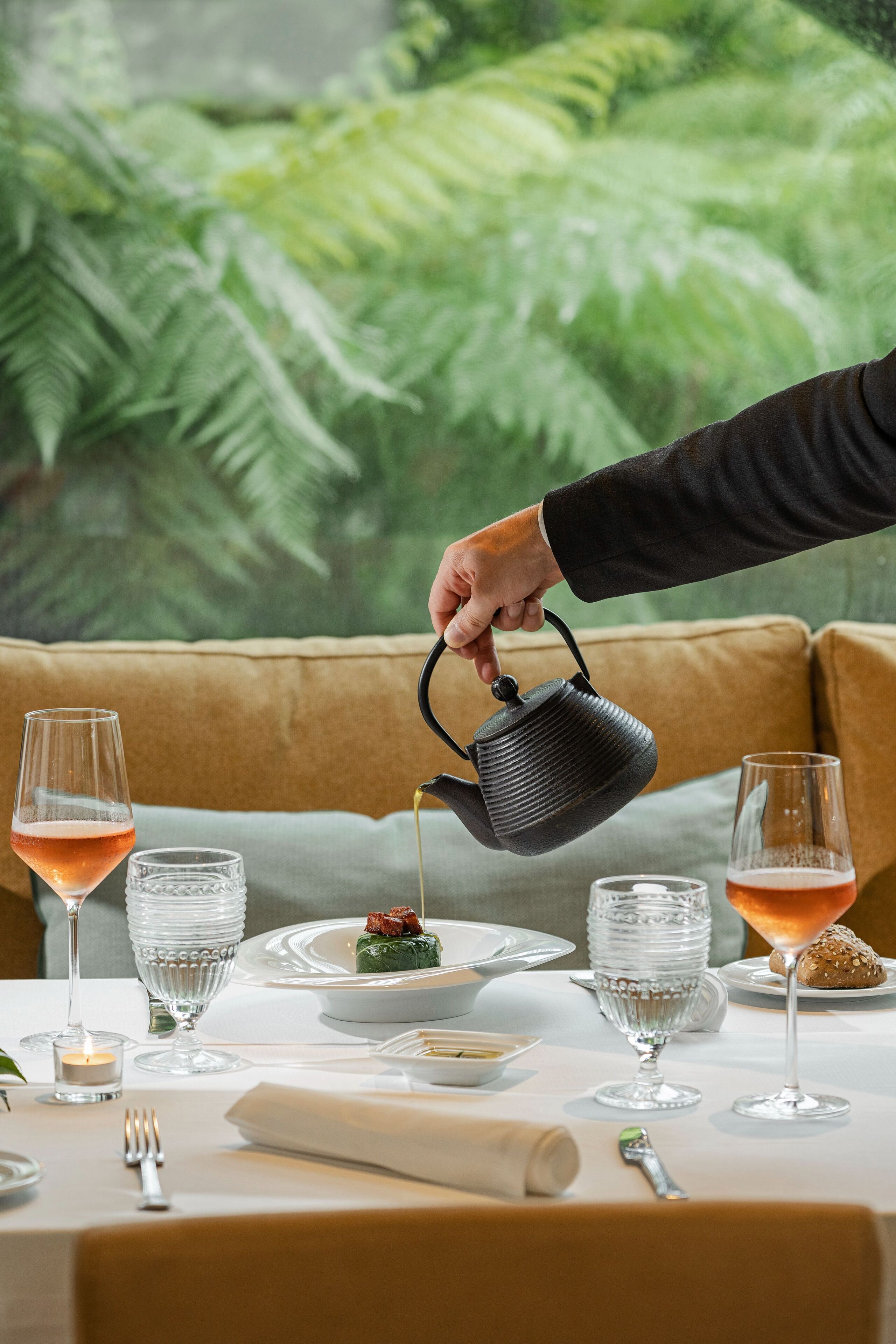 A dining table set with plates, glasses, and a teapot being poured.