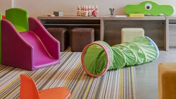 Children can play and relax in this spacious room with a colorful rug, a slide, and a tunnel play structure.