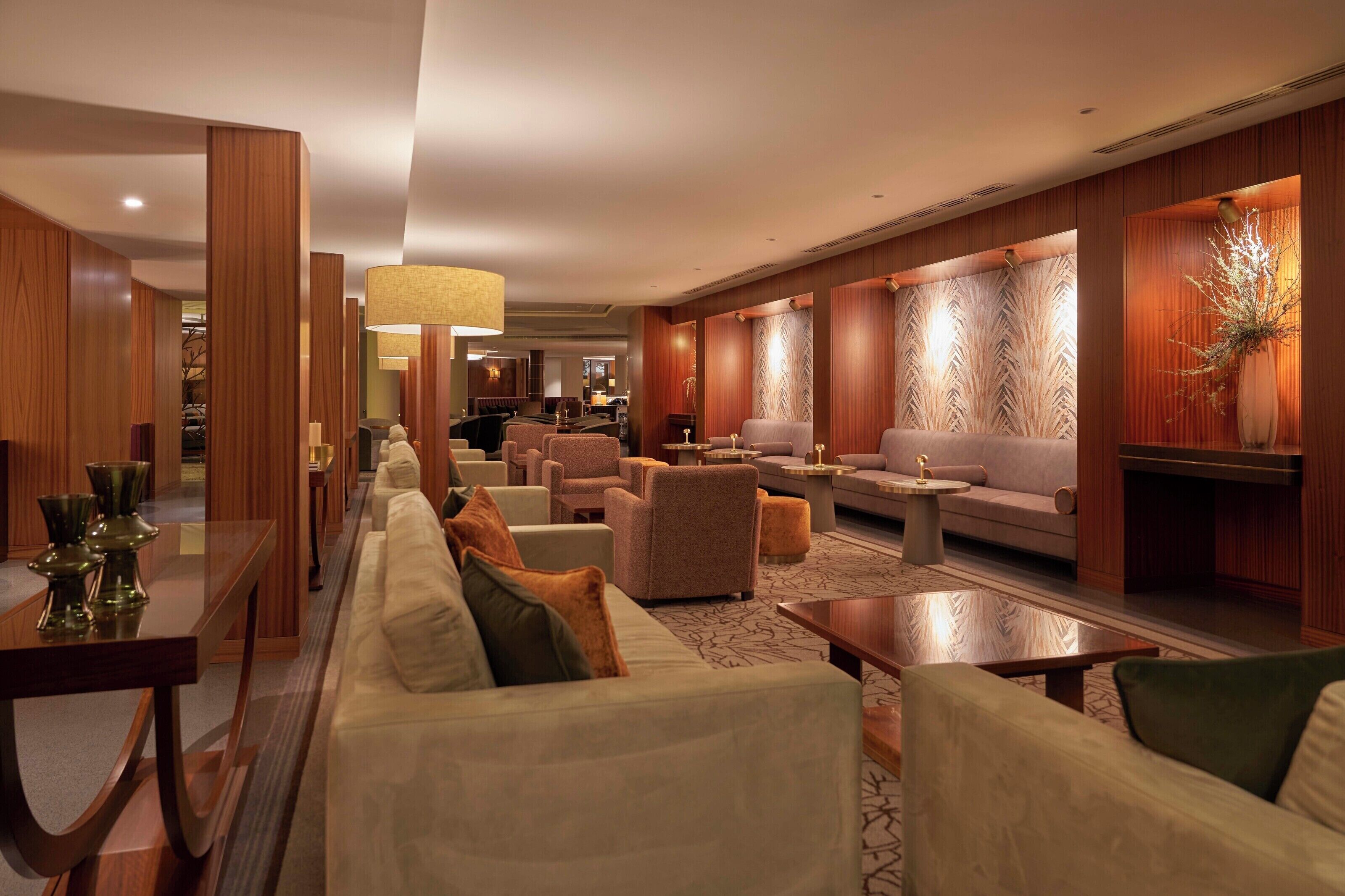 Eine moderne Hotelhalle mit einer langen Couch, Sesseln und einem Essbereich.