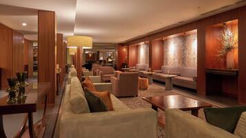 Eine moderne Hotelhalle mit einer langen Couch, Sesseln und einem Essbereich.