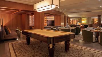 A pool table in a well-lit room with wooden paneling and a patterned carpet.