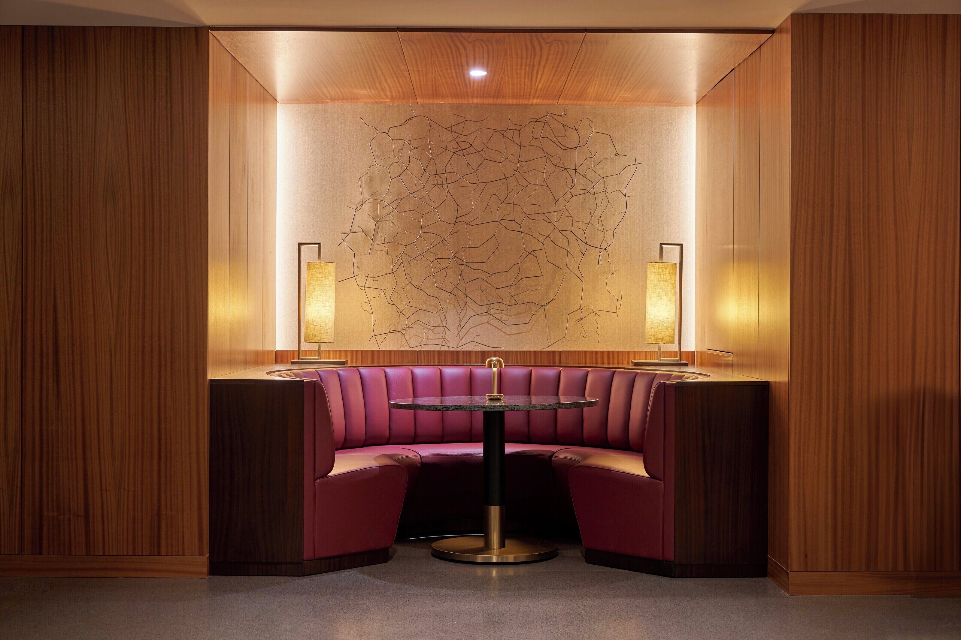 A corner seating area with a round table and two wall-mounted lamps.