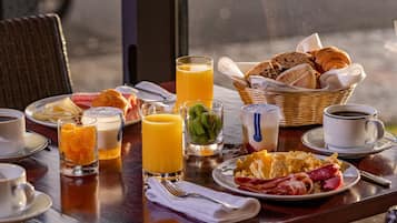 Une table de petit-déjeuner avec des croissants, des œufs, du bacon et du jus de fruits.