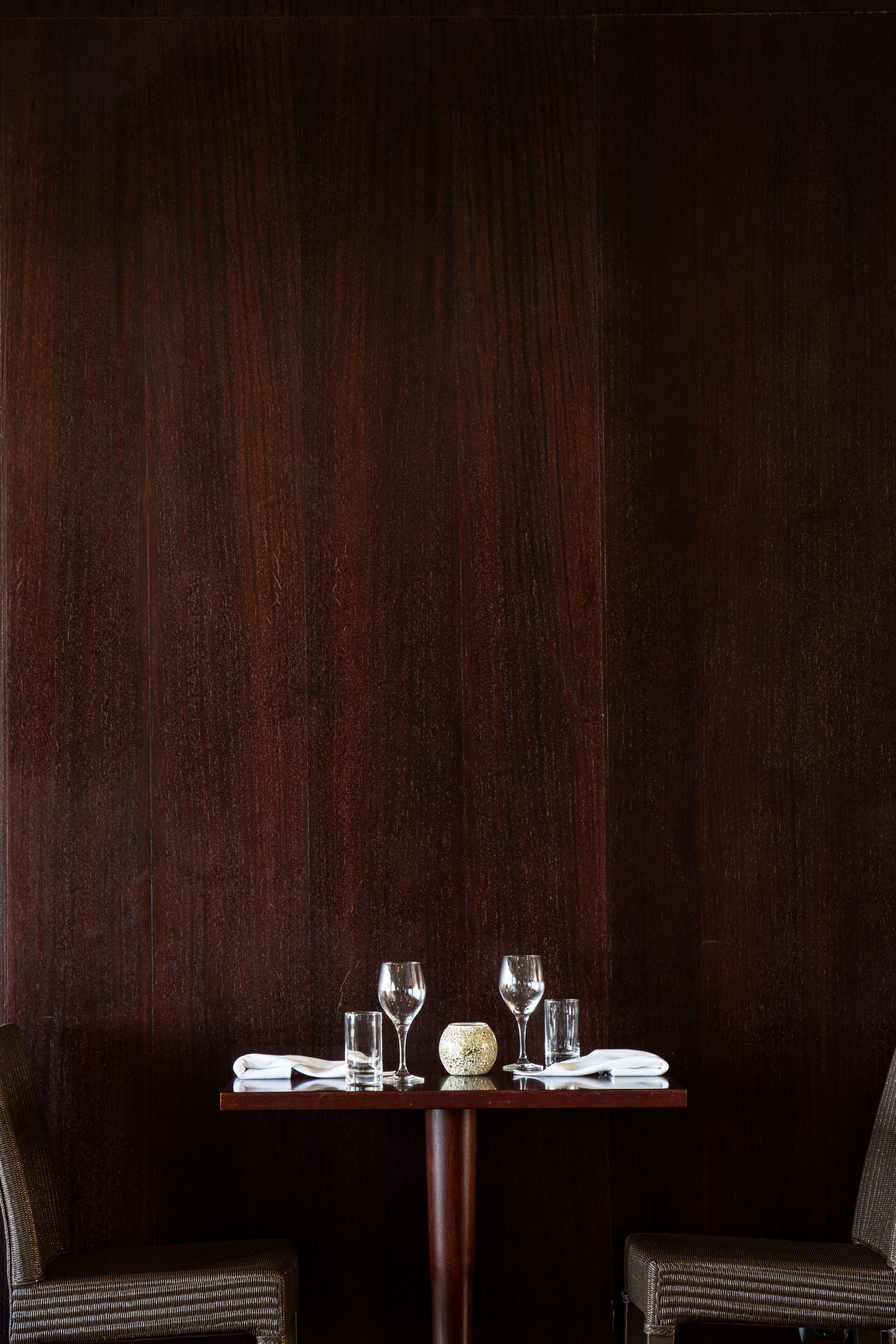 A dining table set with a white plate, two glasses, and a small decorative item.