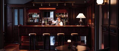 A bar area with stools, a bar counter, and a bartender.