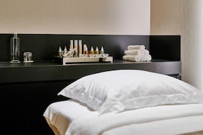 Una habitación de hotel con un mostrador negro, una cama con ropa de cama blanca y toallas dobladas con cuidado.