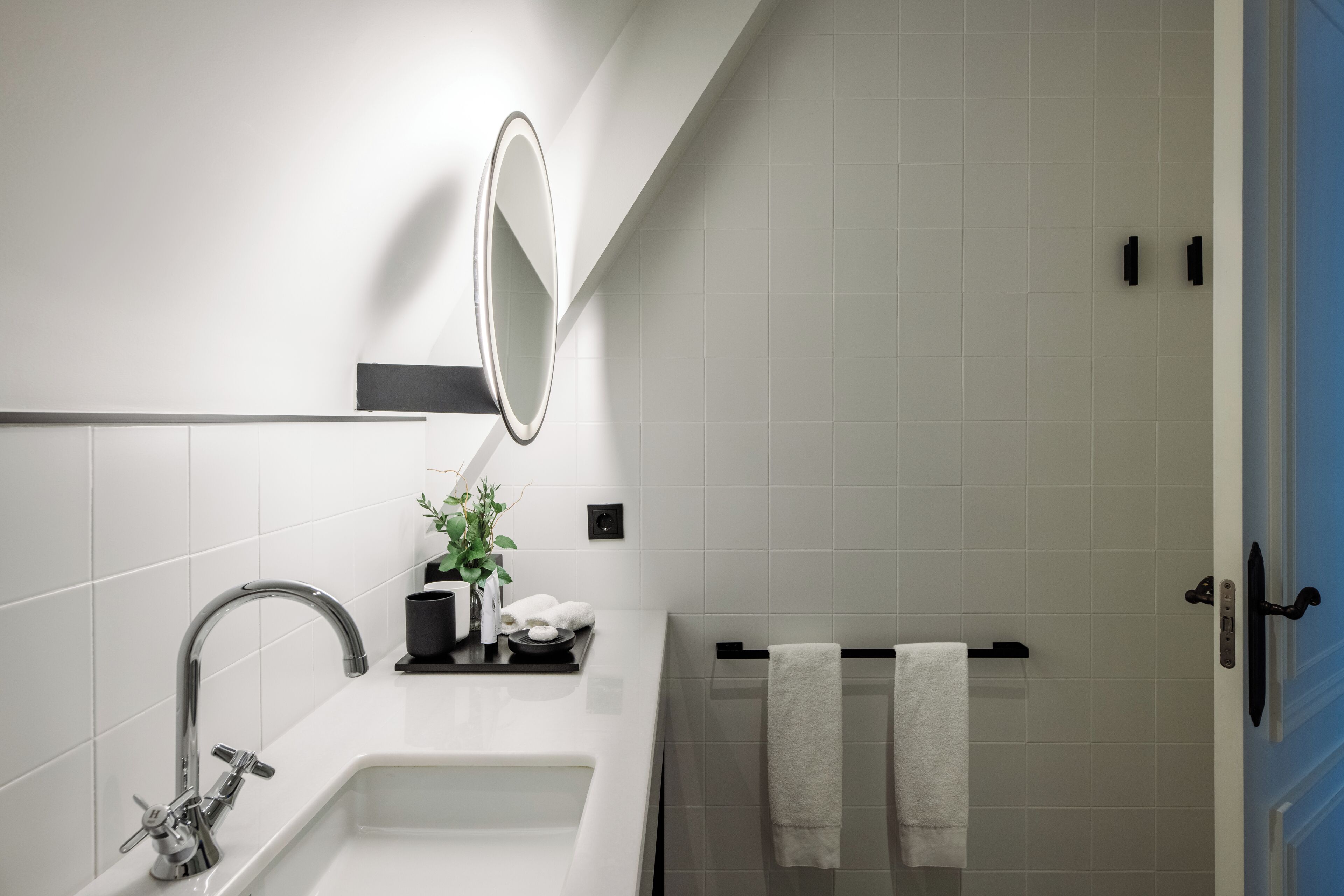 Een moderne badkamer met een wit wastafelmeubel, een spiegel, een handdoekrek en een douche.