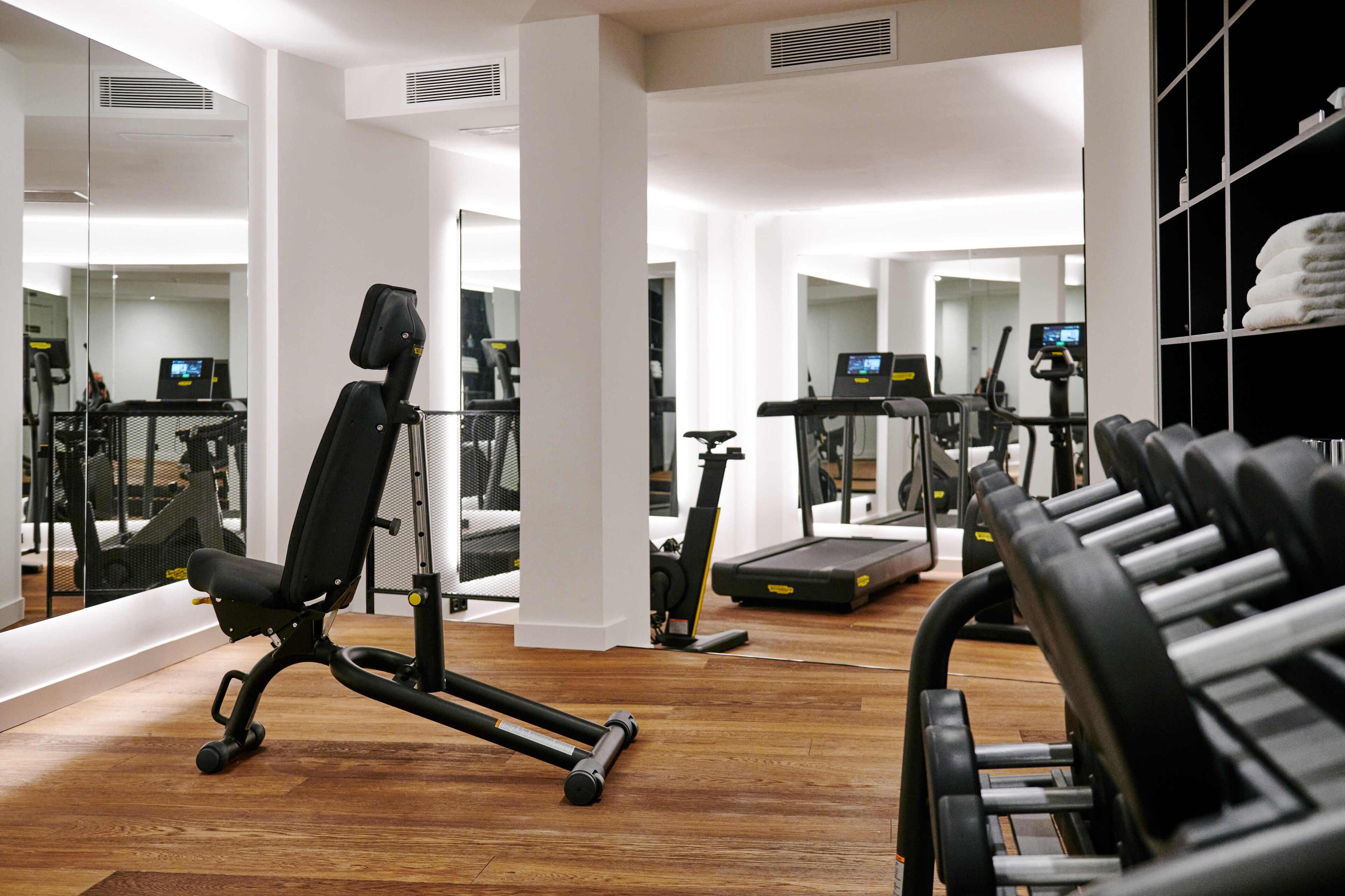 A gym with exercise equipment, wooden flooring, and mirrored walls.