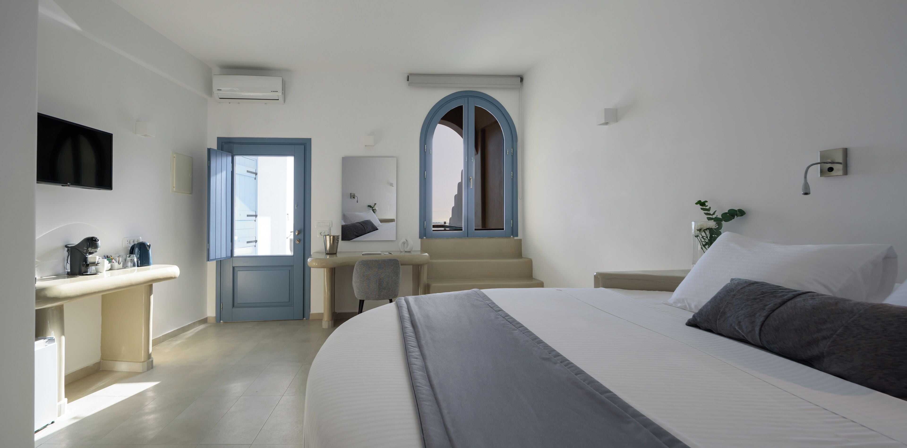 Un dormitorio con cama, escritorio, silla, televisor y ventana.