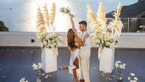 A couple dancing in an outdoor setting with a view of the sea and hills. - Pegasus Spa Hotel (Santorini)
