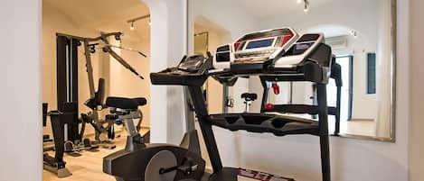 Un gimnasio en casa con cinta de correr, bicicleta estática y máquinas de pesas.