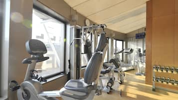 Une salle de sport équipée de matériel d’exercice, dotée de grandes fenêtres et d’un mur en bois.