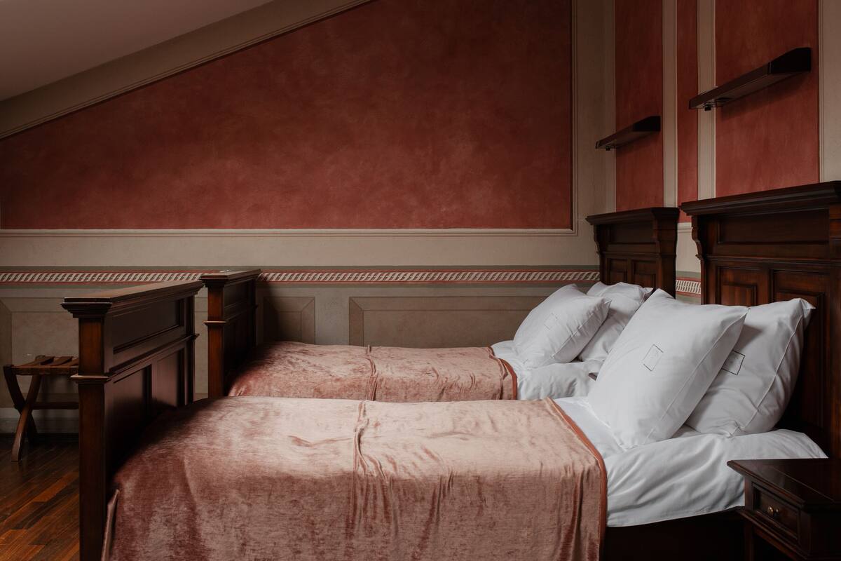 A bedroom with two beds, wooden furniture, and a sloped ceiling.