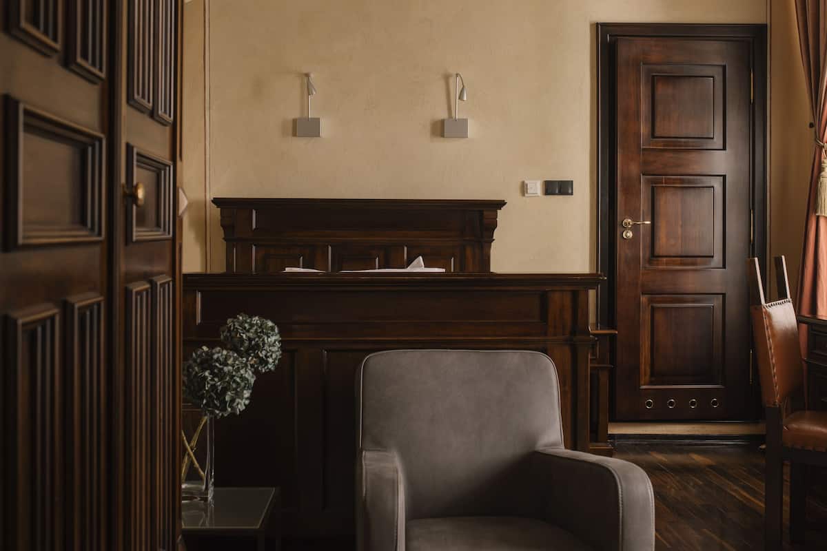 A room with a wooden piano, a chair, and a door.