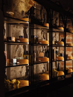 A dimly lit room with a rustic brick wall and shelves containing various items. - Hotel Copernicus (Kraków)