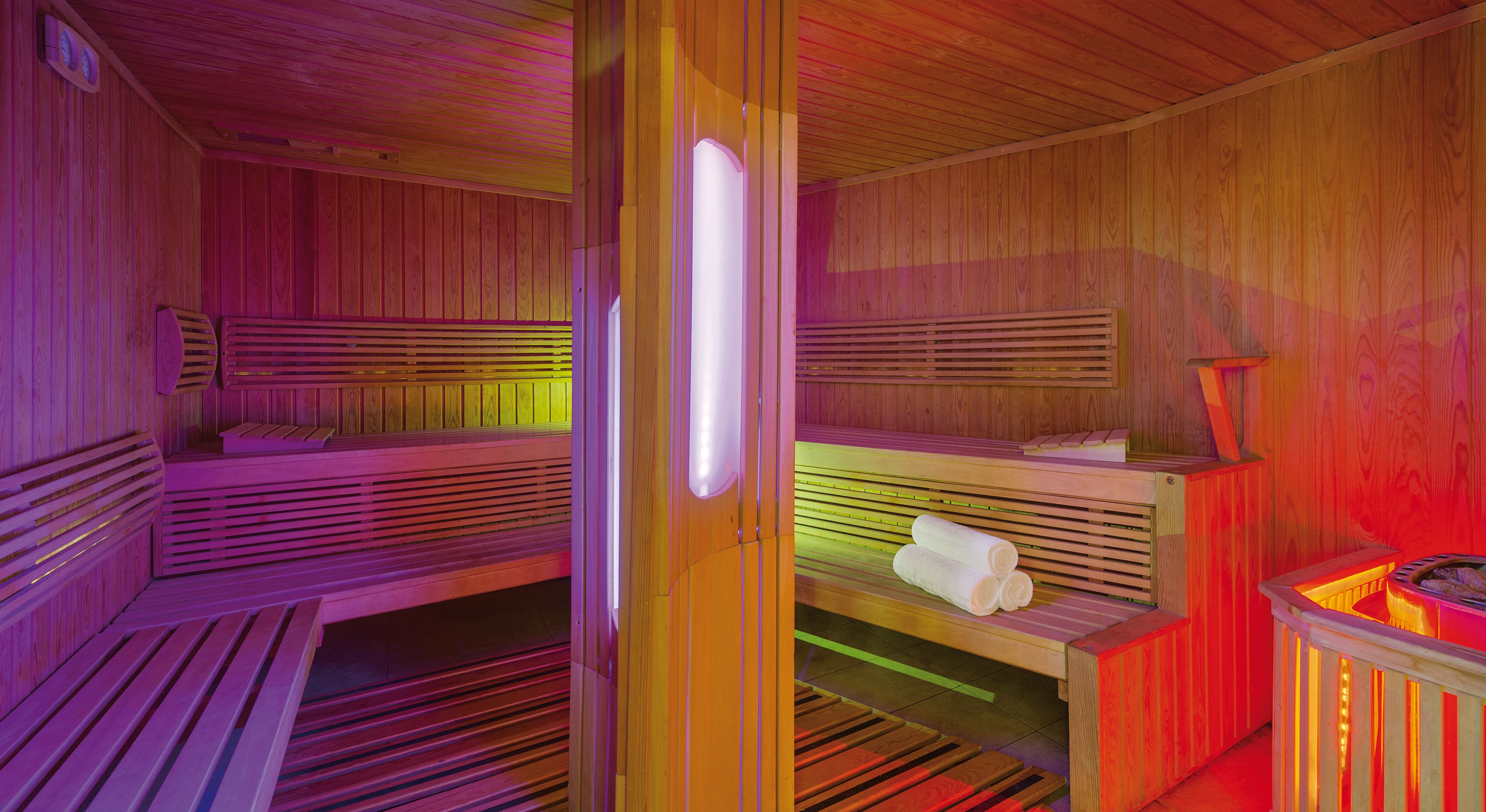 A sauna with wooden benches and a bench with towels.