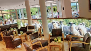 Un restaurante con mobiliario moderno y grandes ventanales con vistas a un jardín.