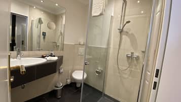 A modern bathroom with a glass-enclosed shower, a sink with a gold faucet, and a toilet.