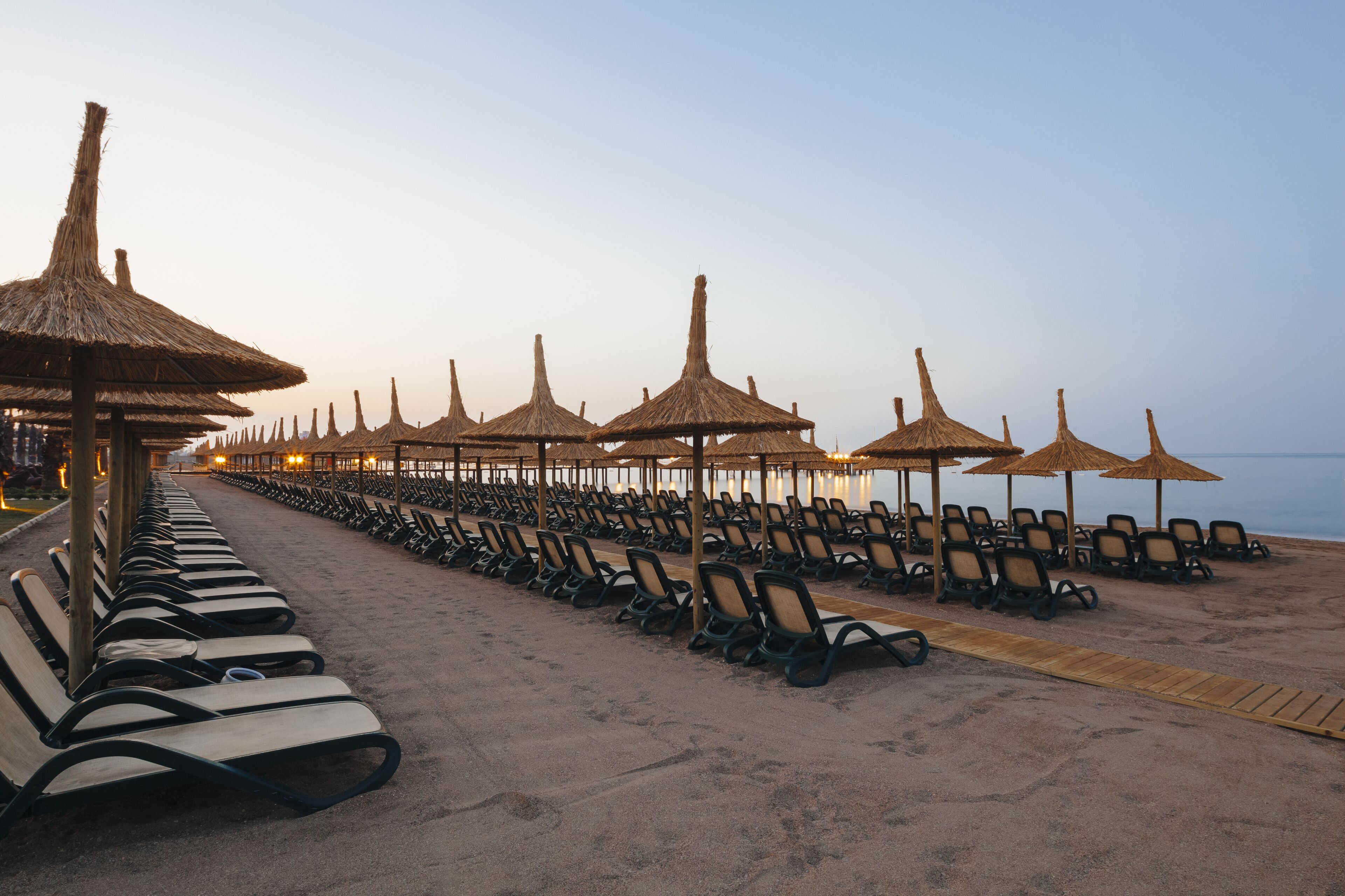 A beach with rows of sun loungers and thatched umbrellas, suggesting a resort setting.