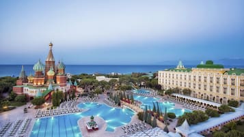 Un resort con varias piscinas, un amplio edificio de hotel e iglesia con cúpulas características.