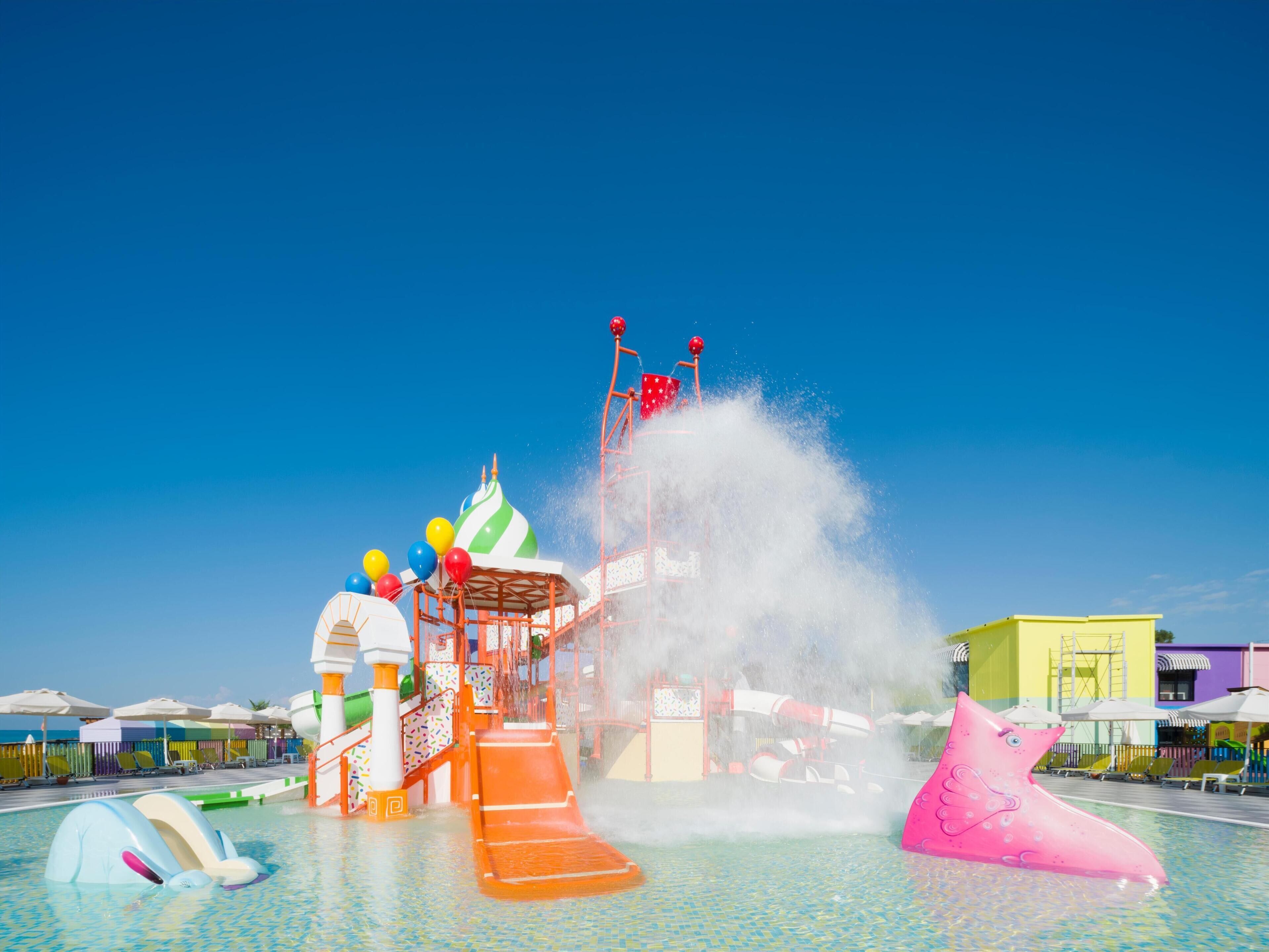 Ein Wasserpark mit Wasserrutsche, aufblasbaren Spielzeugen und Schwimmbecken.