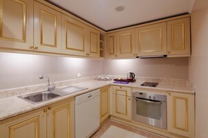 Una cocina con gabinetes color beige, un lavamanos de acero inoxidable, un lavavajillas y un horno.