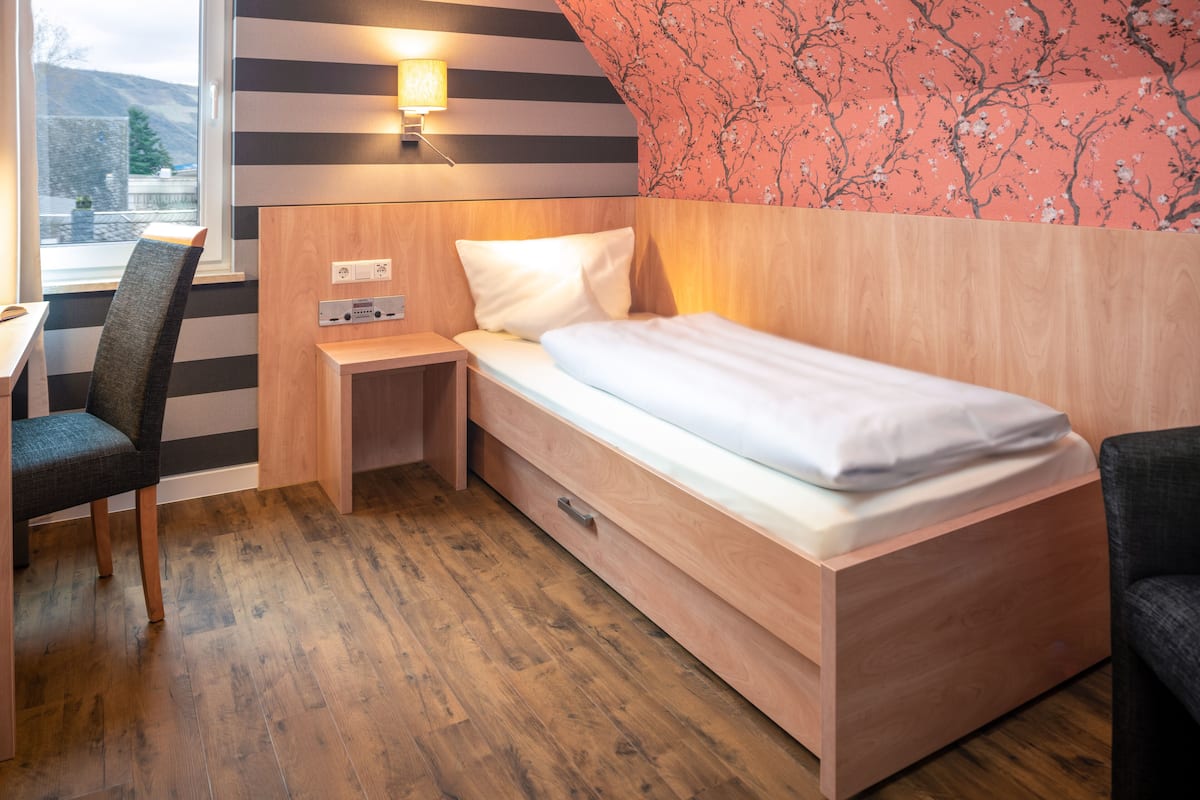 A compact hotel room with a bed, a desk, and a chair.