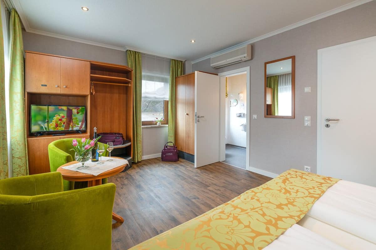 A hotel room with a bed, a TV, a desk with a chair, and a wardrobe.