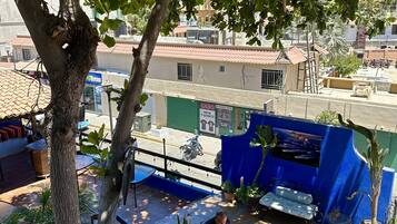 A terrace with a blue awning, potted plants, and a seating area.