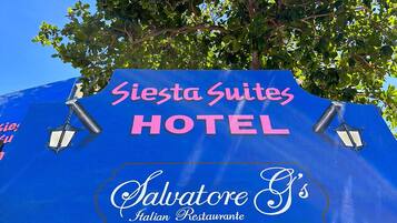 Schild für das Siesta Suites Hotel, im Hintergrund ein Baum.