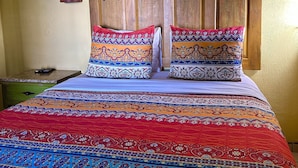 A bed with a wooden headboard, two decorative pillows, and a patterned bedspread. - Siesta Suites Boutique Hotel (Cabo San Lucas)