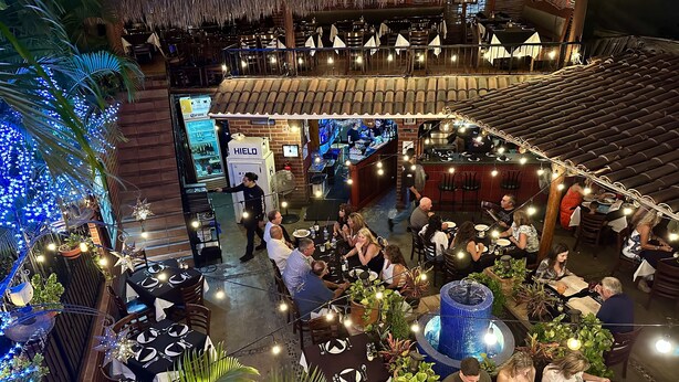 An outdoor dining area with tables and chairs, surrounded by plants and string lights. - Siesta Suites Boutique Hotel (Cabo San Lucas)
