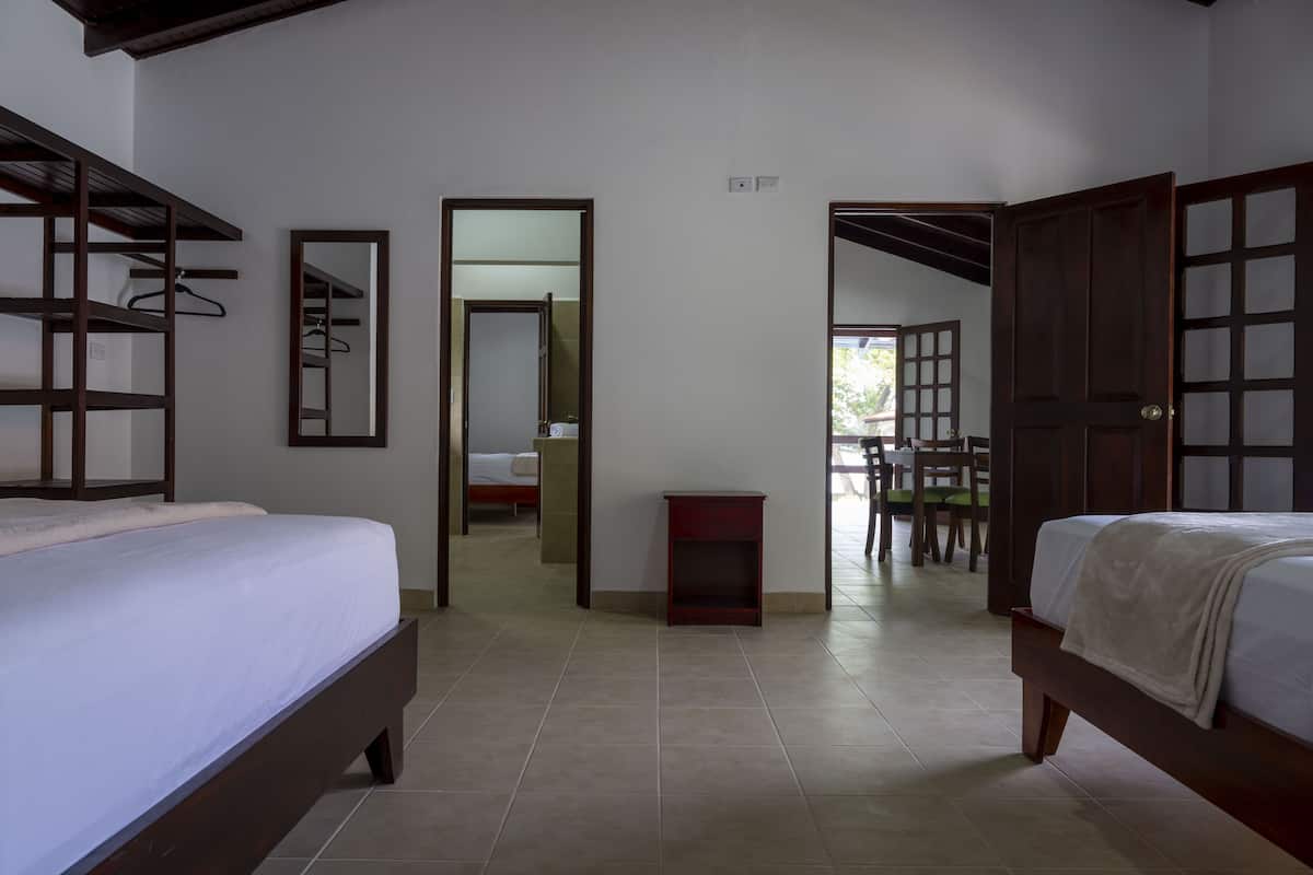 A bedroom with two beds, a wardrobe, a mirror, and a small table.