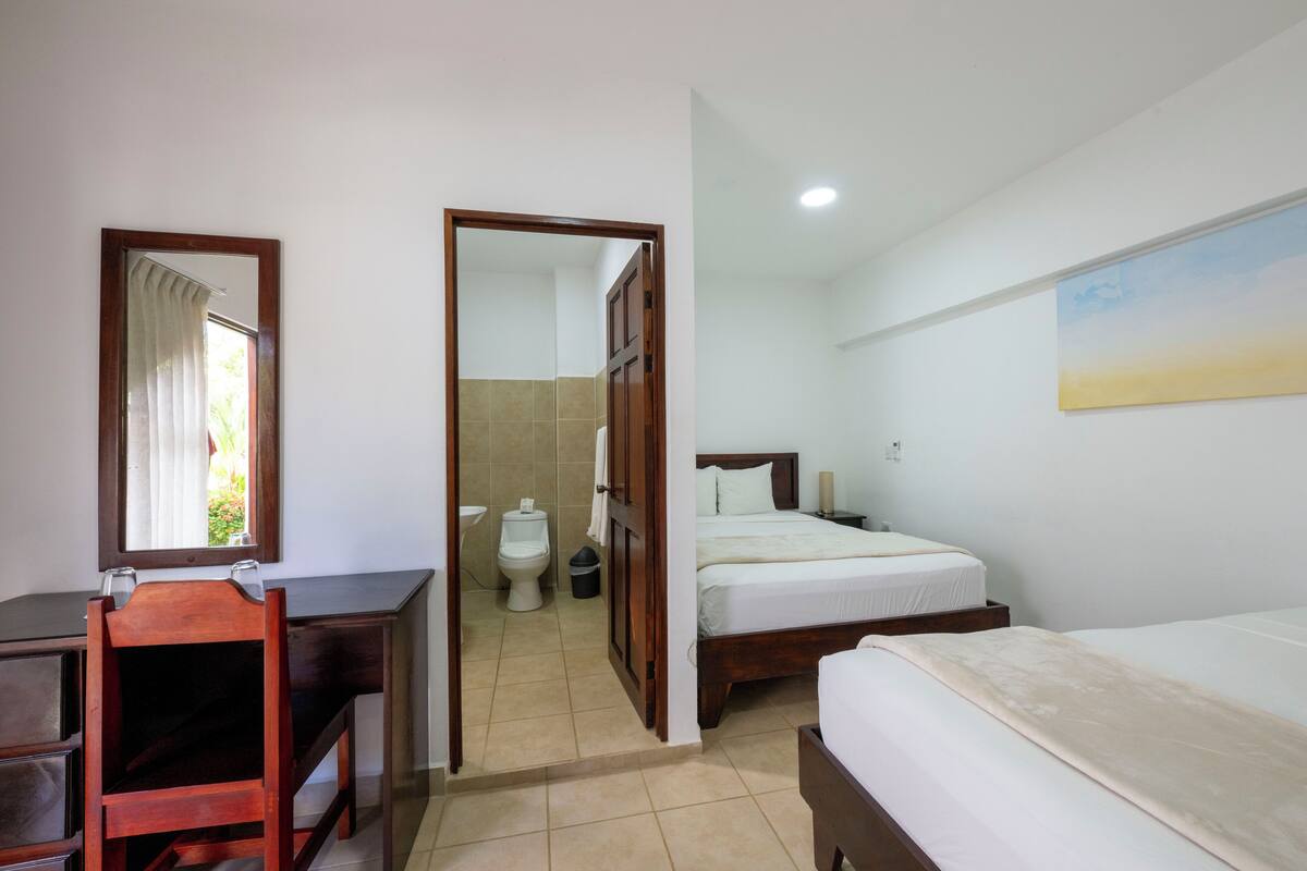 A bedroom with a wooden bed, a desk, and a mirror.