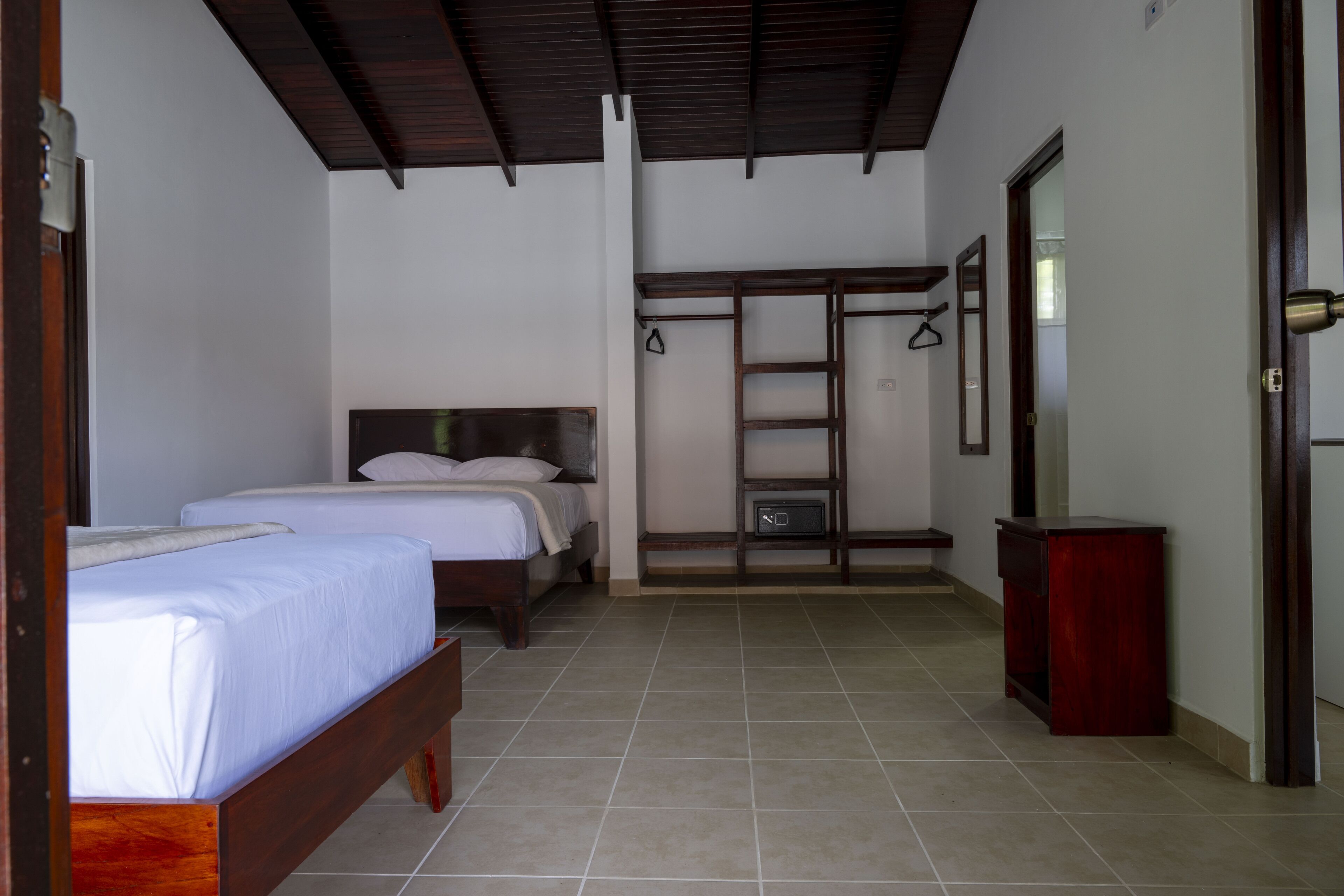 A bedroom with two beds, a wardrobe, and a small cabinet.