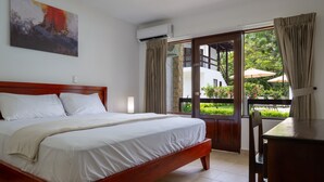 A hotel room with a wooden bed, a desk, and a balcony with outdoor furniture. - Fuego del Sol Beachfront Hotel (Jacó)